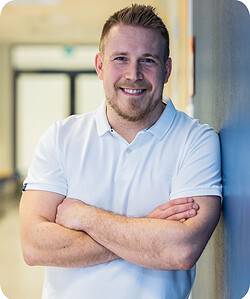 Foxstudy Coach smiles with his arms crossed in a neutral office setting.